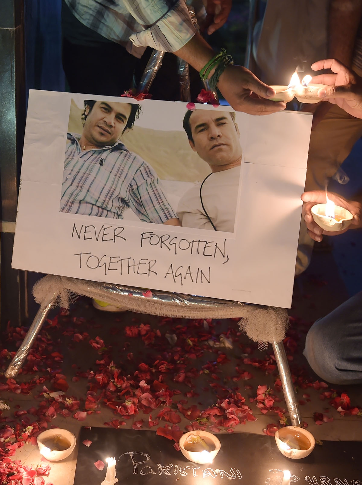 Periodistas prenden velas junto a las fotografías de Shah Marai y su amigo y colega de AFP Sardar Ahmad (izquierda), quien murió en un atentado en Kabul en 2014