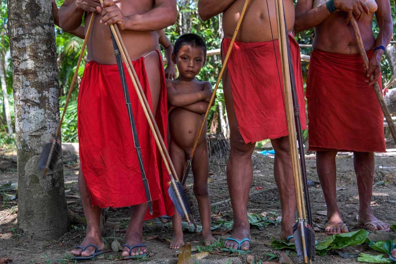 A Waiapi boy stands behind adults at the Pinoty village in Waiapi indigenous reserve in Amapa state in Brazil on October 12, 2017. Tribal chieftain Tzako Waiapi perfectly remembers the day almost half a century ago when his hunting party stumbled across