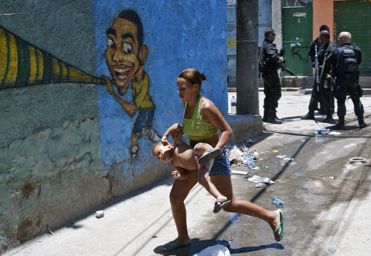 Residents flee during a police raid in the Morro do Alermao favela in Rio de Janeiro, November 28, 2010.