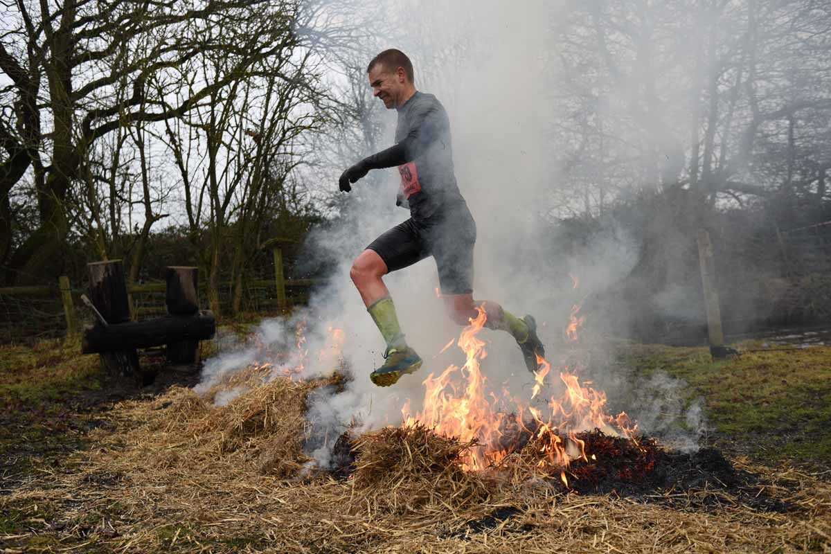 A competitor jumps a burning bale of hay as he takes part in the 'Tough Guy' adventure race near Wolverhampton, central England, on January 29, 2017. The Tough Guy event, which is being held for the final time in its 30th year, challenges thousands of co