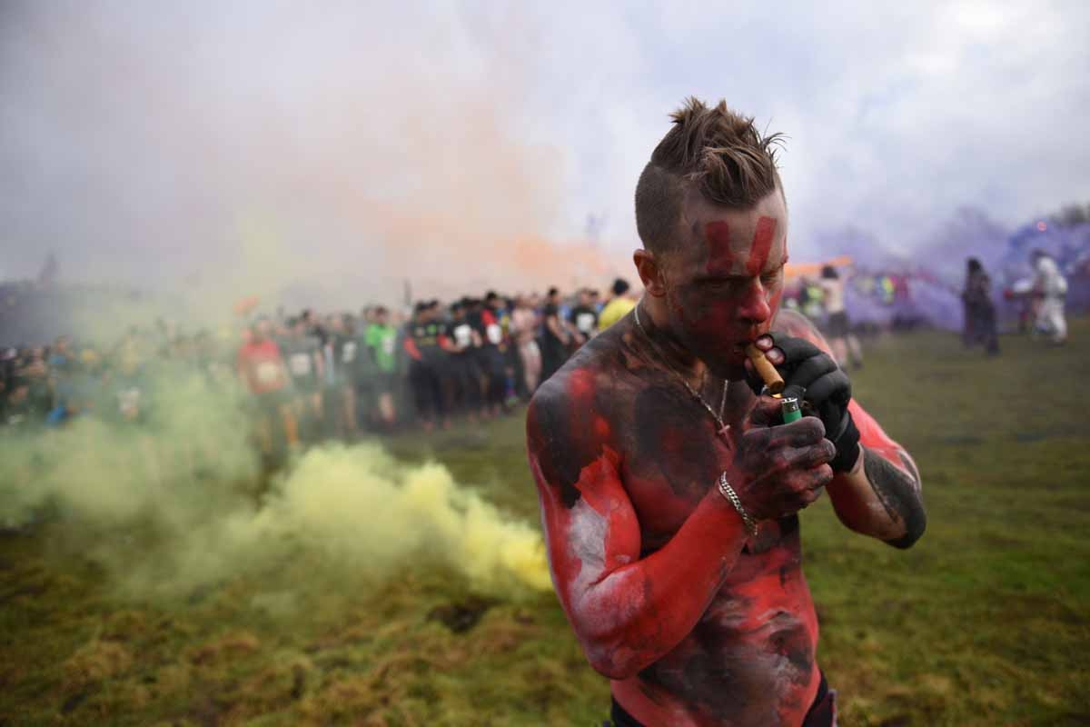 A man with a painted torso lights a cigar before the start of the 'Tough Guy' adventure race near Wolverhampton, West Midlands, on January 29, 2017. The Tough Guy event, which is being held for the final time in its 30th year, challenges thousands of comp