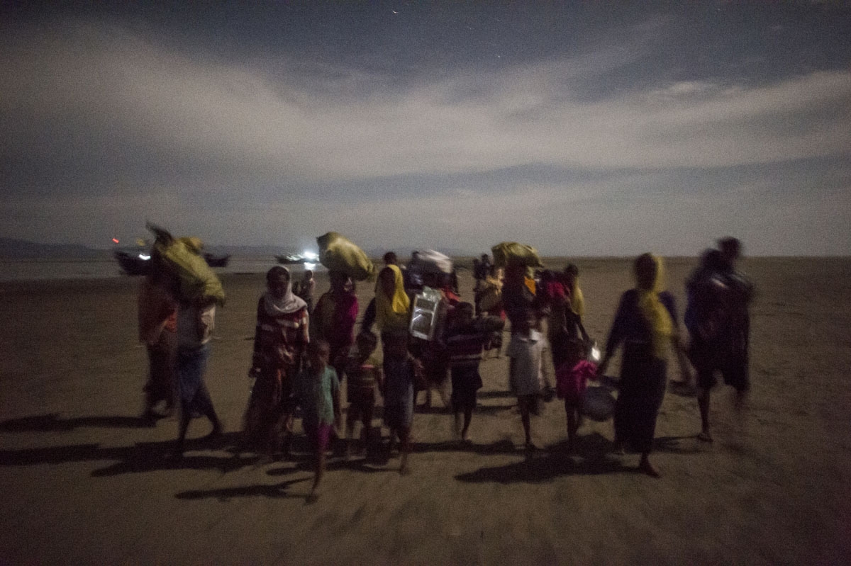 Rohingya Muslim refugees walk by night after crossing the border from Myanmar, on the Bangladeshi shores of the Naf river in Teknaf on September 29, 2017.