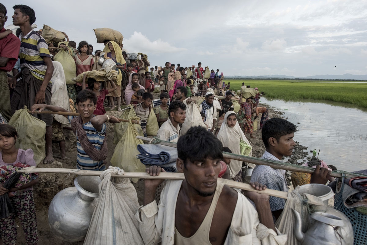 Rohingya refugees walk with their belongings after crossing the Naf river from Myanmar into Bangladesh in Whaikhyang on October 9, 2017.