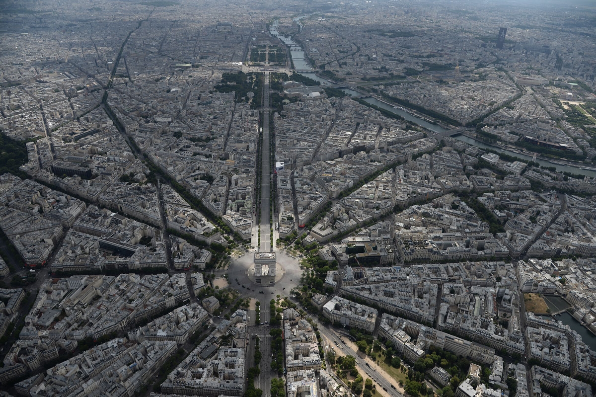 A picture taken on July 14, 2017, in Paris, shows an aerial view of the Arc de Triomphe de l'Etoile standing at the western end of the Champs-Elysees avenue and at the center of Place Charles de Gaulle and with the river Seine on the background. / A