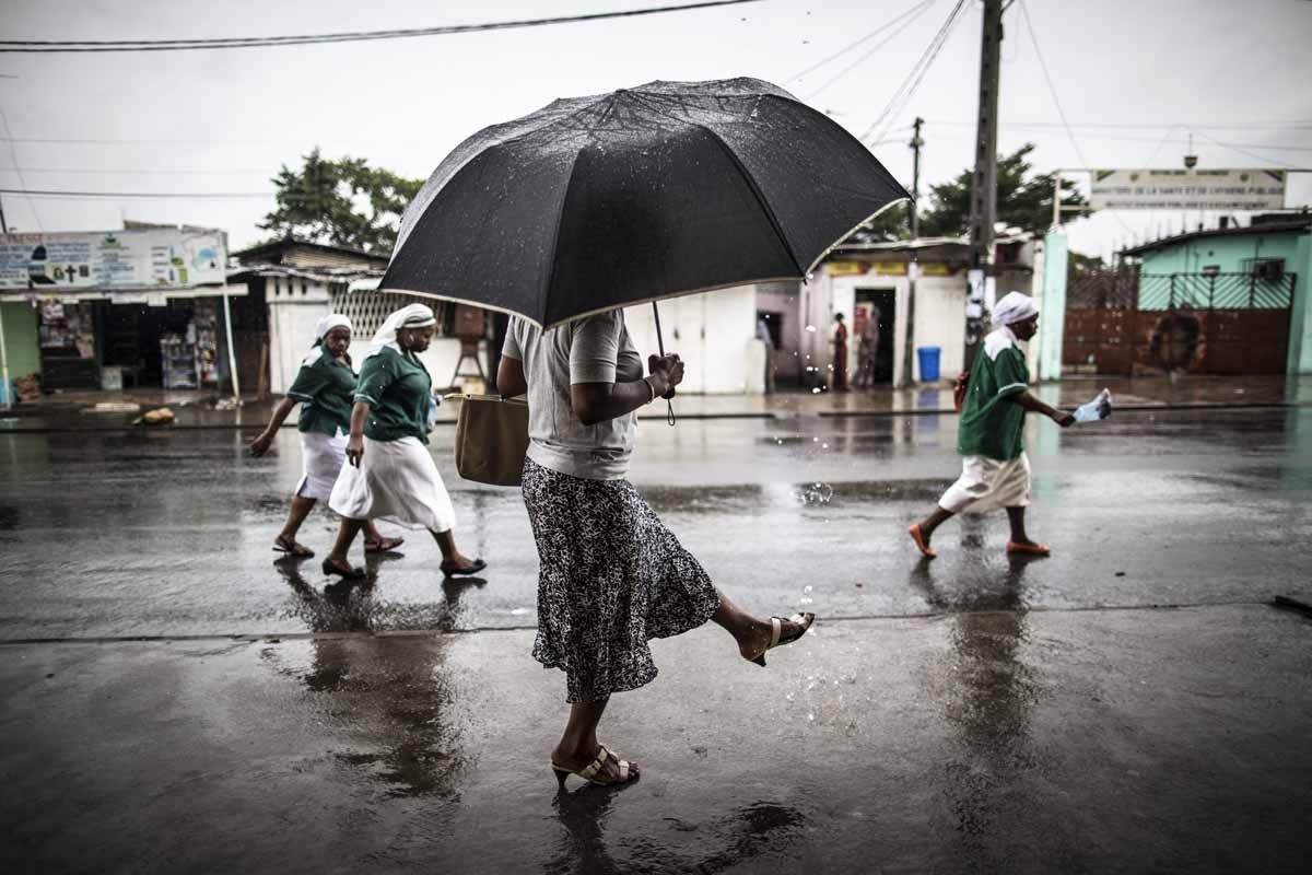 A woman washes a her foot with water streaming out of a pipe as catholic nuns leave the St. Michel Church in Libreville on August 28, 2016 after the Sunday's service.