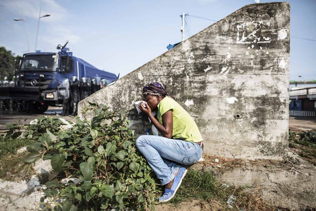 A Gabonese woman takes cover protecting her mouth from the tear gas as supporters of opposition leader Jean Ping protest, trying to reach the electoral commission, in Libreville on August 31, 2016.