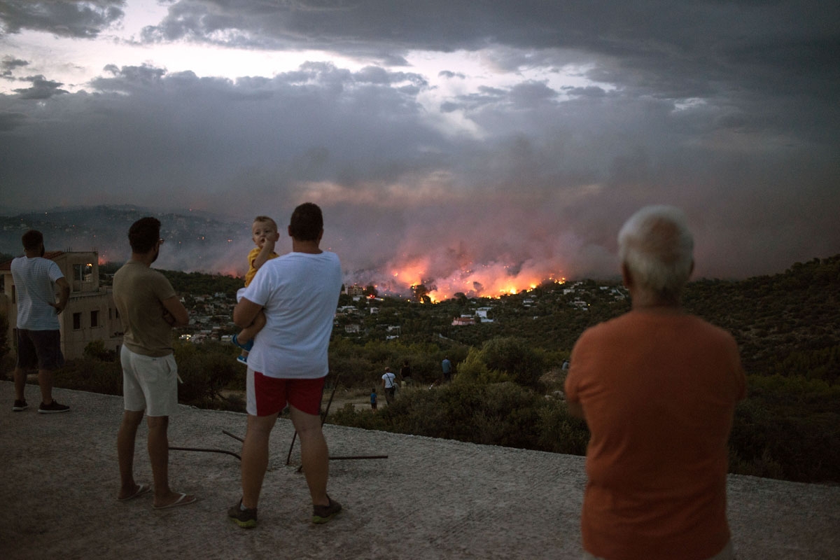 People watch a wildfire in the town of Rafina, near Athens, on July 23, 2018.