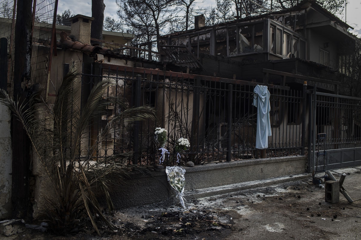 A picture taken on July 26, 2018 shows flowers on a fence of a house where two bodies where found following a wildfire at the village of Mati, near Athens.