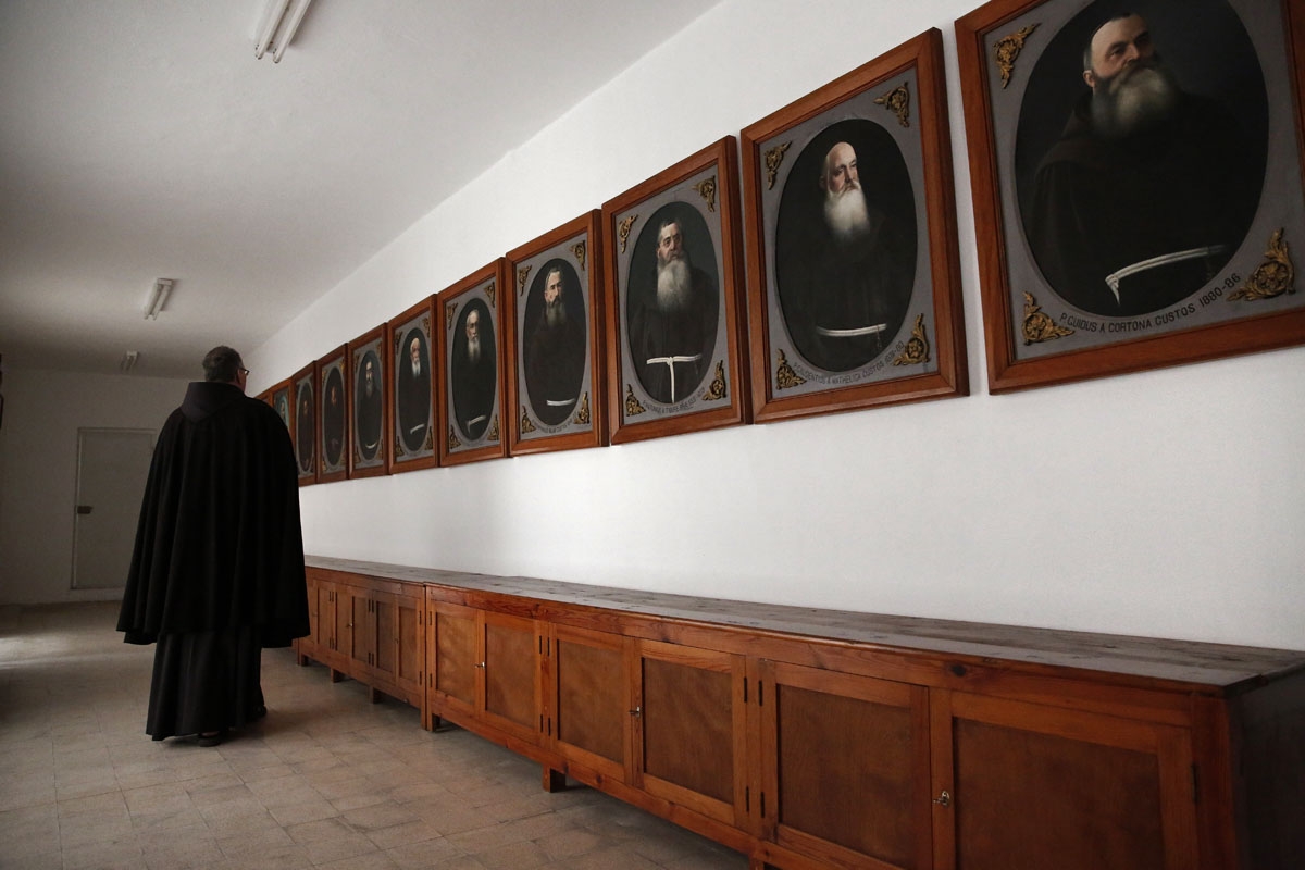 A Franciscan friar walks past the portraits of former Custos placed in a dedicated room at the St Saviour Monastery, the Franciscan headquarters in the Old City of Jerusalem, on January 25, 2018.