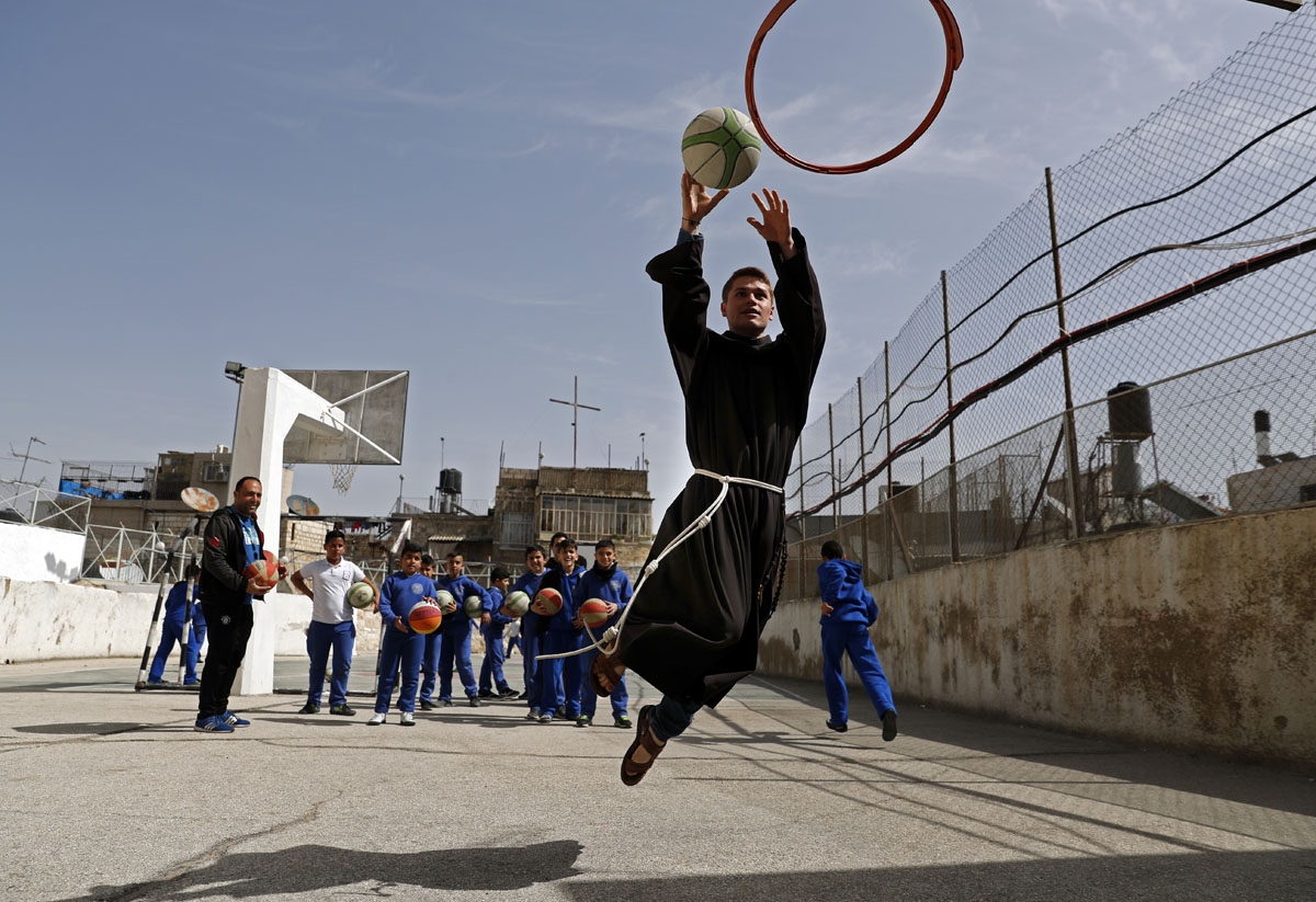 A Franciscan friar plays basketball with Palestinian children from the Terra Sancta school during a sport session in the Old City of Jerusalem, on March 1, 2018.