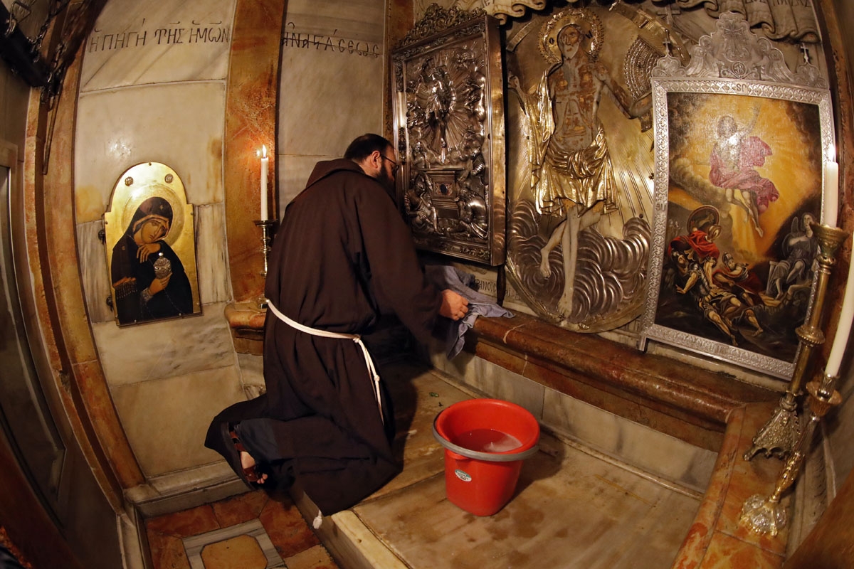 Croatian friar Sinisa Srebrerovic cleans the ornaments inside a tomb believed to the burial site of Jesus Christ on March 2, 2018.