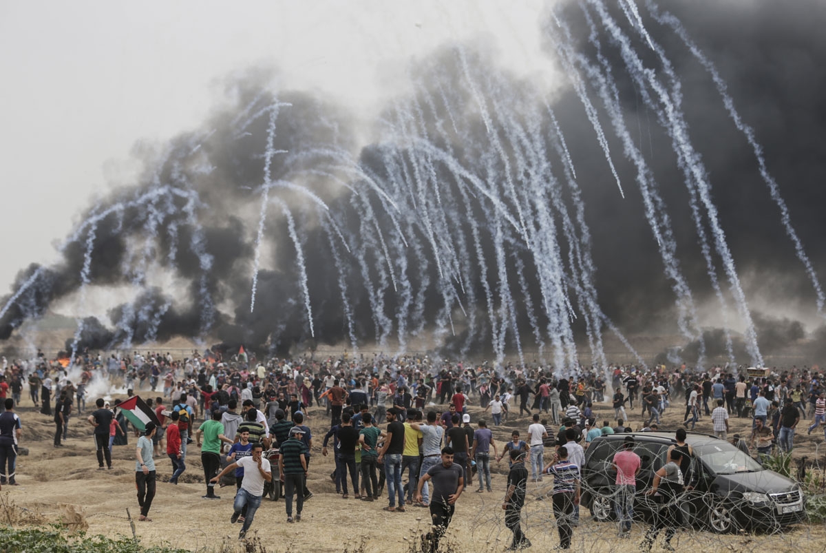 Palestinian protesters flee from incoming teargas canisters during clashes with Israeli forces along the border with the Gaza strip east of Gaza City on May 4, 2018, on the sixth straight Friday of mass demonstrations calling for the right to return to th