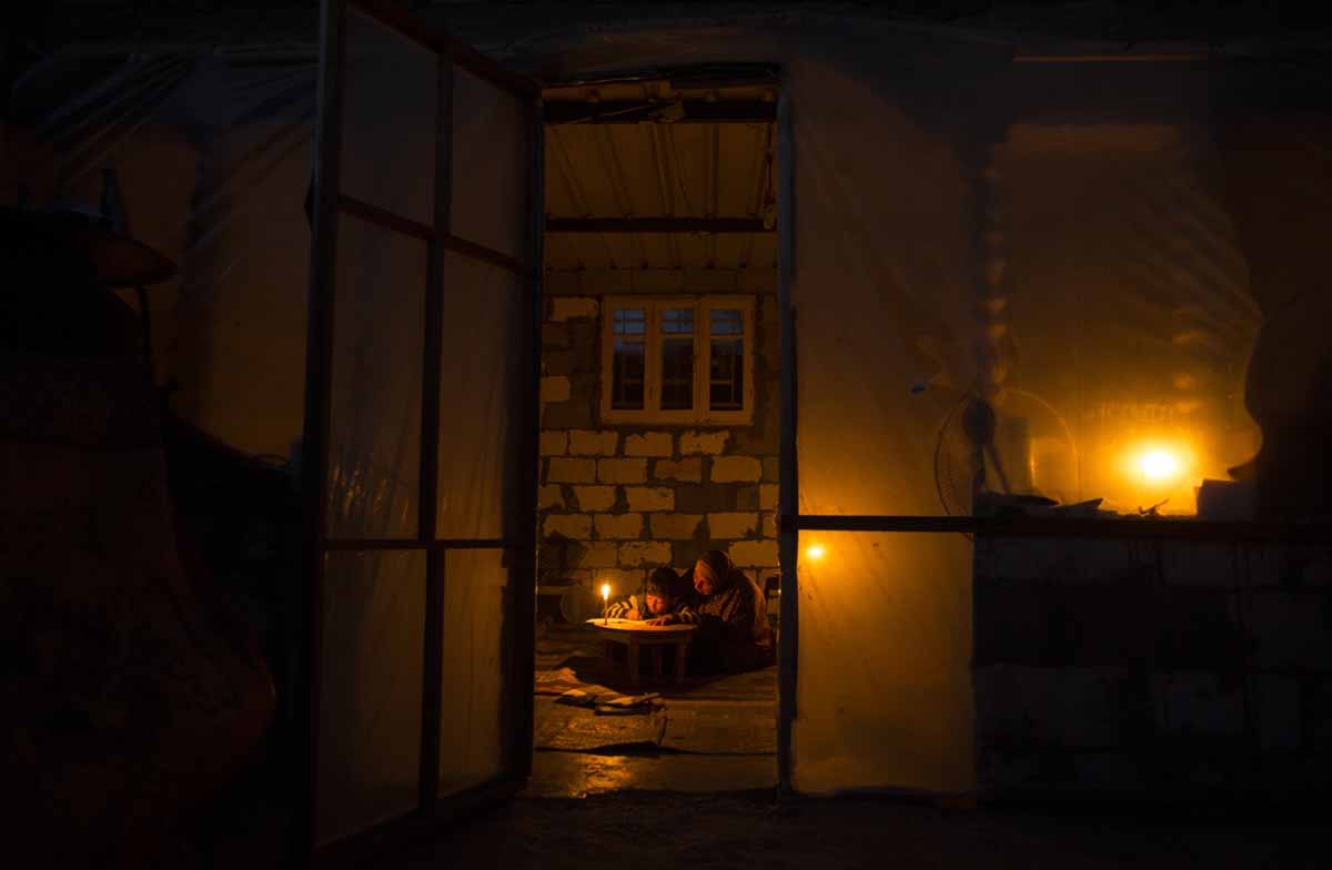 Una mujer palestina estudia con un niño a la luz de una vela en el campo de refugiados Khan Yunis en Gaza, en abril de 2017.