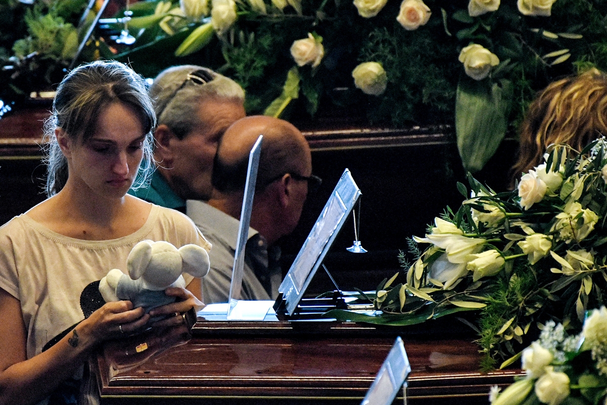 A relative holds a teddy bear as she mourns near the coffin of a victim of the collapsed Morandi highway bridge, prior to the start of the funeral service, in Genoa, on August 18, 2018.