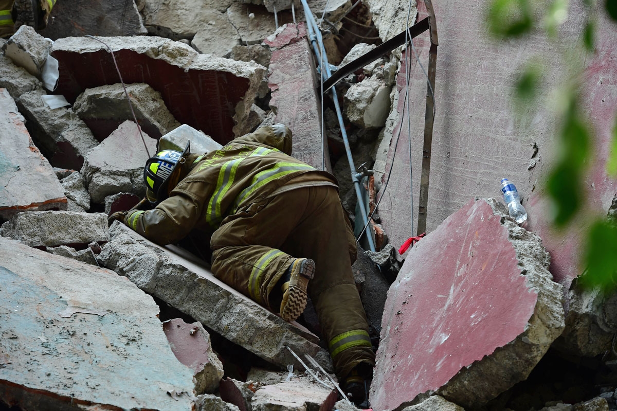 Rescuers, firefighters, policemen, soldiers and volunteers remove rubble and debris from a flattened building in search of survivors after a powerful quake in Mexico City on September 19, 2017. A devastating quake in Mex