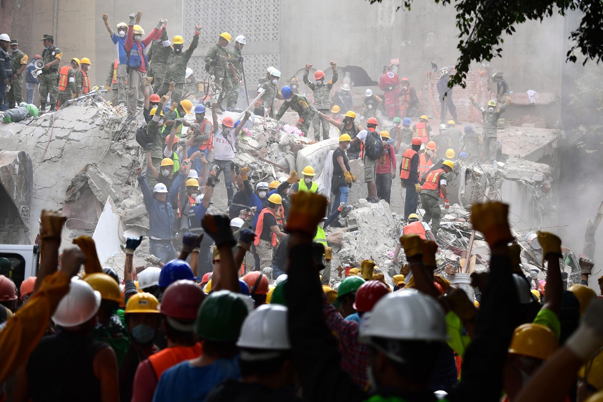 Rescuers make the signal for silence during the search for survivors in a flattened building in Mexico City on September 21, 2017, two days after a strong quake hit central Mexico killing at least 240 people.