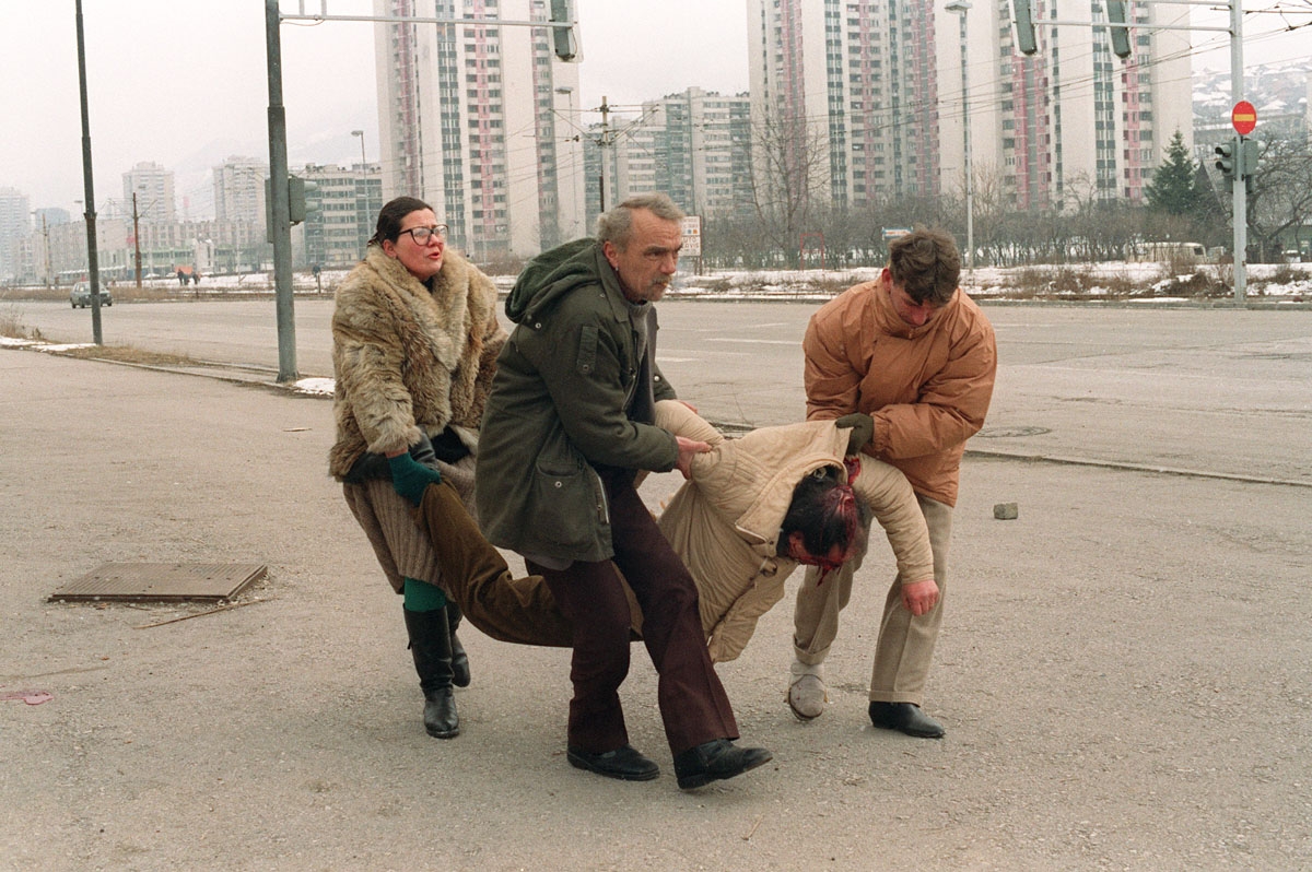 People carry away 08 March 1993 in Sarajevo a man wounded by a shell which fell near the television station during the Serb forces shelling of the Bosnia-Herzegovina capital.
