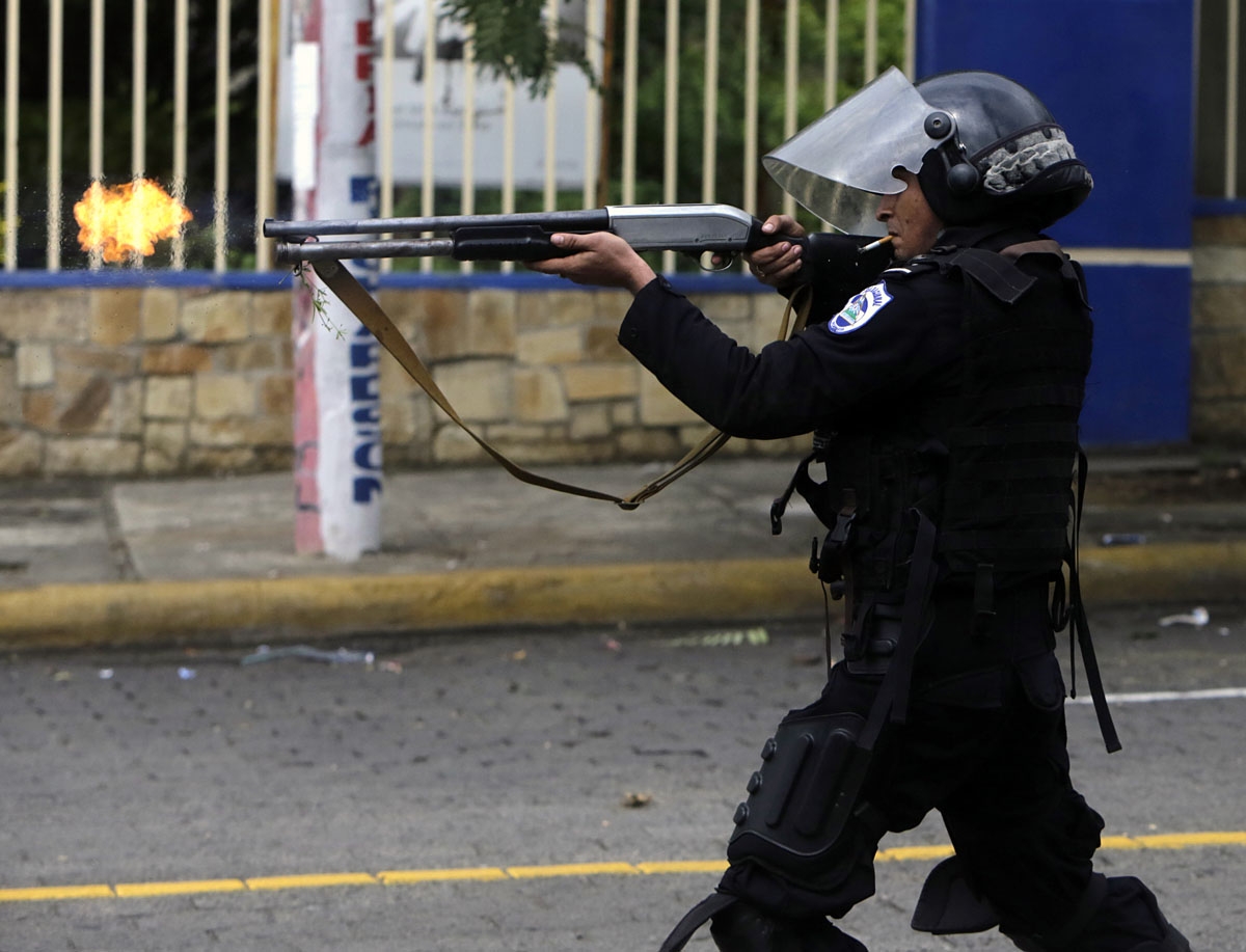 A riot police officer fires a weapon during clashes with students taking part in a protest in Managua on May 28, 2018.