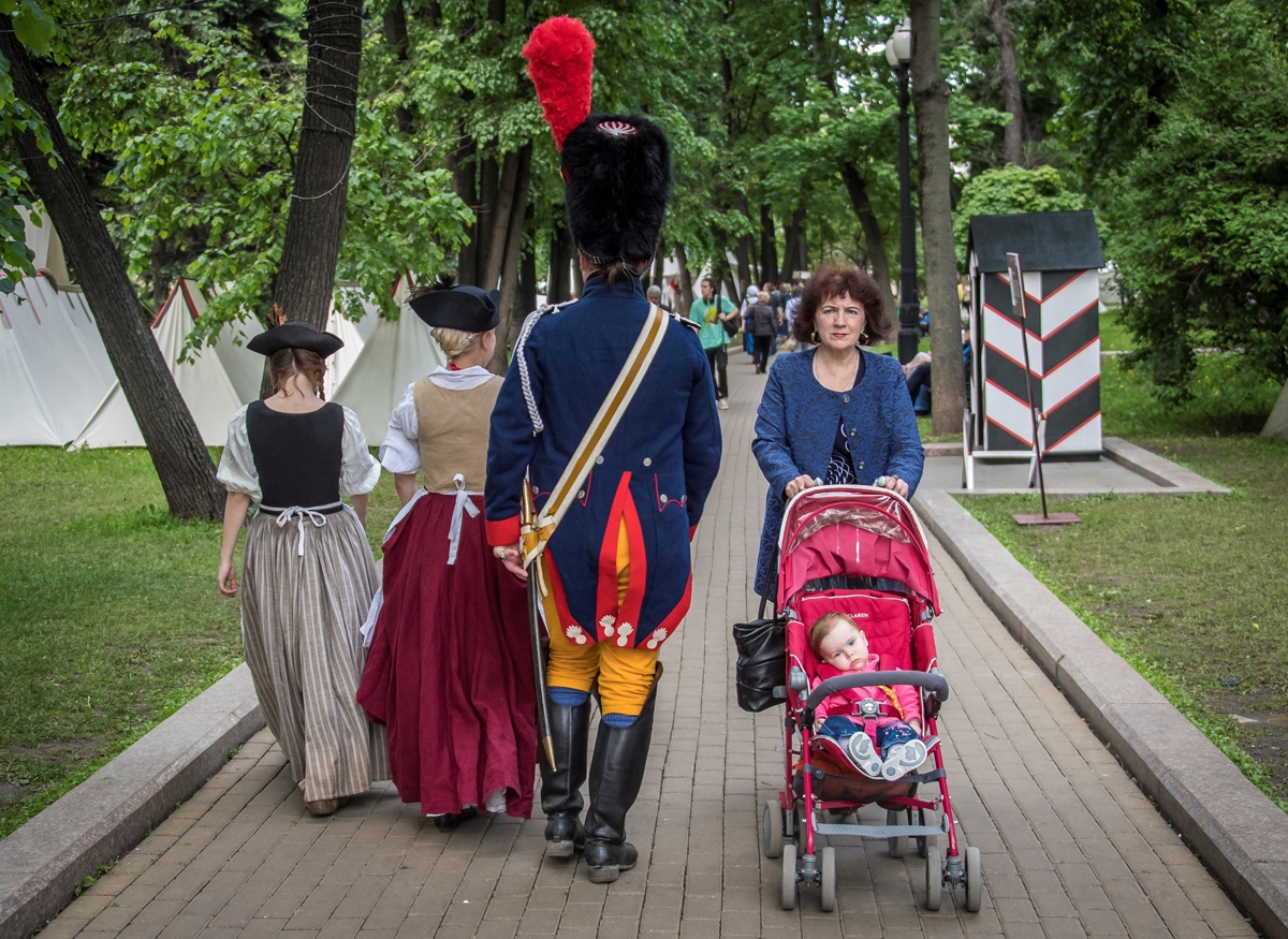 Una mujer con una sillita de niño camina junto a unos ciudadanos vewstidos con trajes de 1812 en una feria en el centro de Moscú, el 8 de junio de 2017