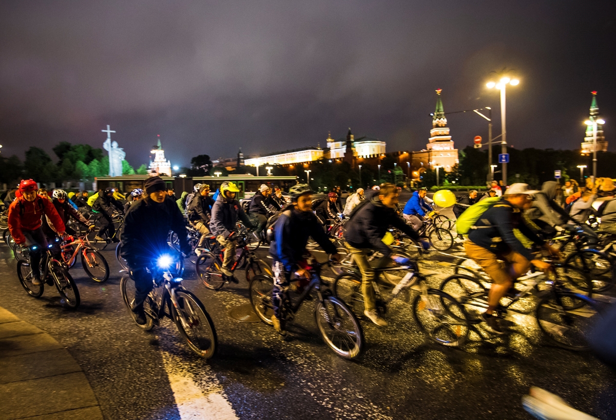 People ride bycicles in front of the Kremlin during the annual night velo parade cycling event gathering thousands of enthusiasts on the streets of Moscow on July 8, 2017.