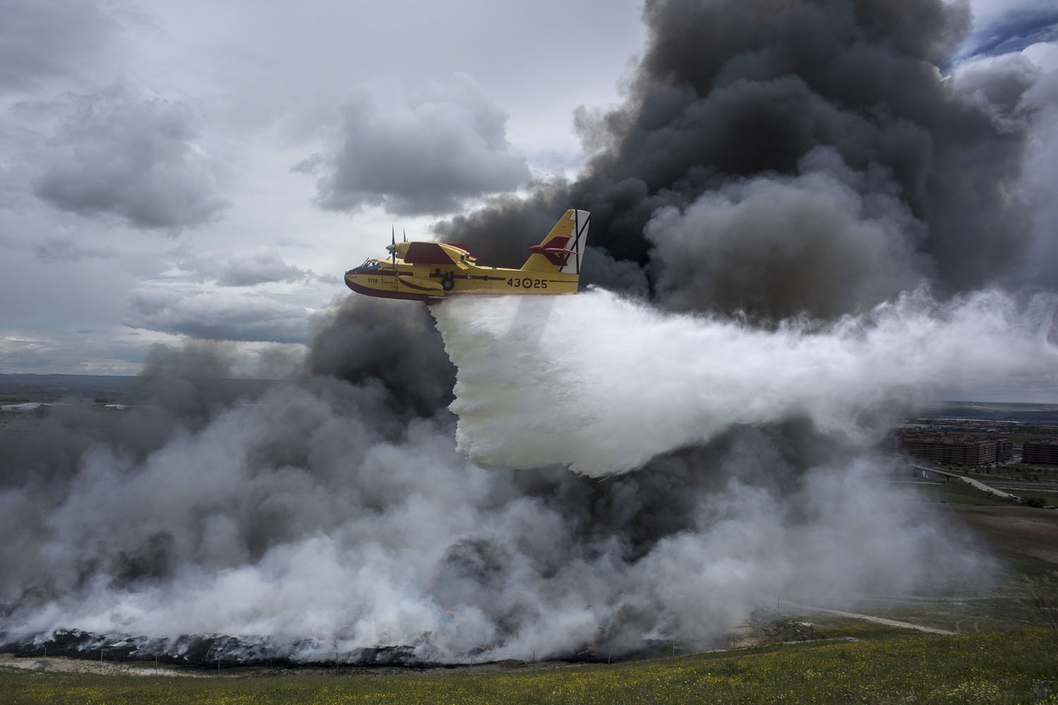 A seaplane discharges water over the tyres burning in an uncontrolled dump near the town of Sesena, after a fire brokeout early on May 13, 2016 A seaplane discharges water over the tyres burning in an uncontrolled dump near the town of Sesena, after a fire brokeout early on May 13, 2016
