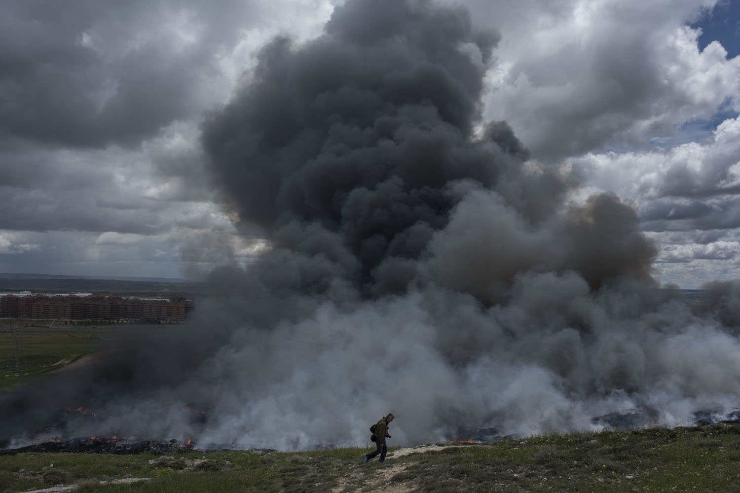 A man walks past a pile of tyres burning in an uncontrolled dump near the town of Sesena, after a fire brokeout early on May 13, 2016 A man walks past a pile of tyres burning in an uncontrolled dump near the town of Sesena, after a fire brokeout early on May 13, 2016