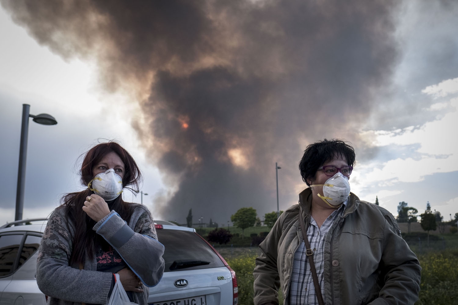 Two neighbours of Sesena wear masks as they wait for other relatives to evacuate a residential area affected by th toxic fumes produced by tyres burning in an uncontrolled dump Two neighbours of Sesena wear masks as they wait for other relatives to evacuate a residential area affected by th toxic fumes produced by tyres burning in an uncontrolled dump
