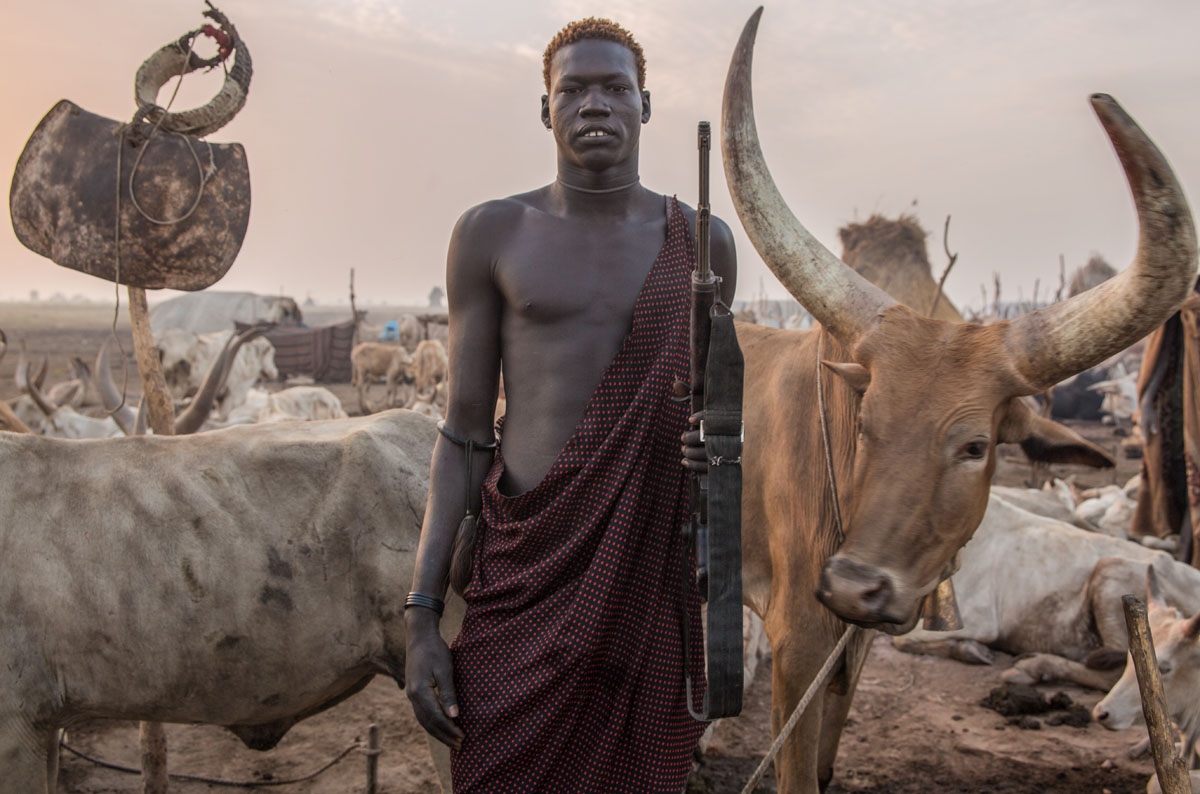 A Sudanese man from Dinka tribe poses with a rifle in the early morning at their cattle camp in Mingkaman, Lakes State, South Sudan on March 4, 2018.