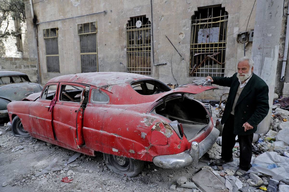 A picture taken on March 9, 2017, shows 70-year-old Mohammad Mohiedine Anis opening the trunk of his 1949 Hudson Commodor outside his home in Aleppo's formerly rebel-held al-Shaar neighbourhood.