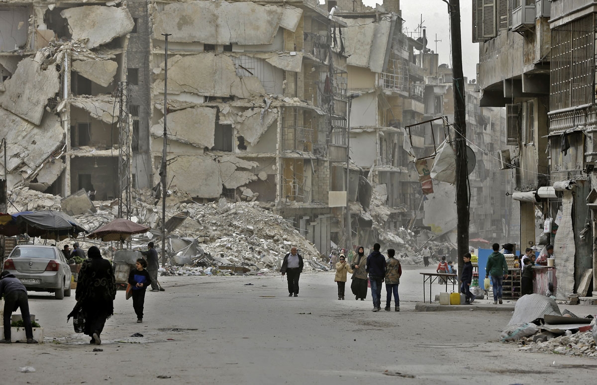 Syrians walk in the once rebel-held al-Shaar neighbourhood in the northern city of Aleppo on March 10, 2017