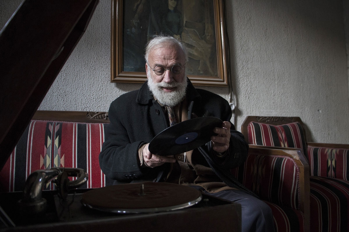 Abu Omar a 69-year-old Syrian classic car collector, holds a vinyl next to a record player in his apartment in the rebel held al-Shaar district of the northern Syrian city of Aleppo, on December 20, 2015.