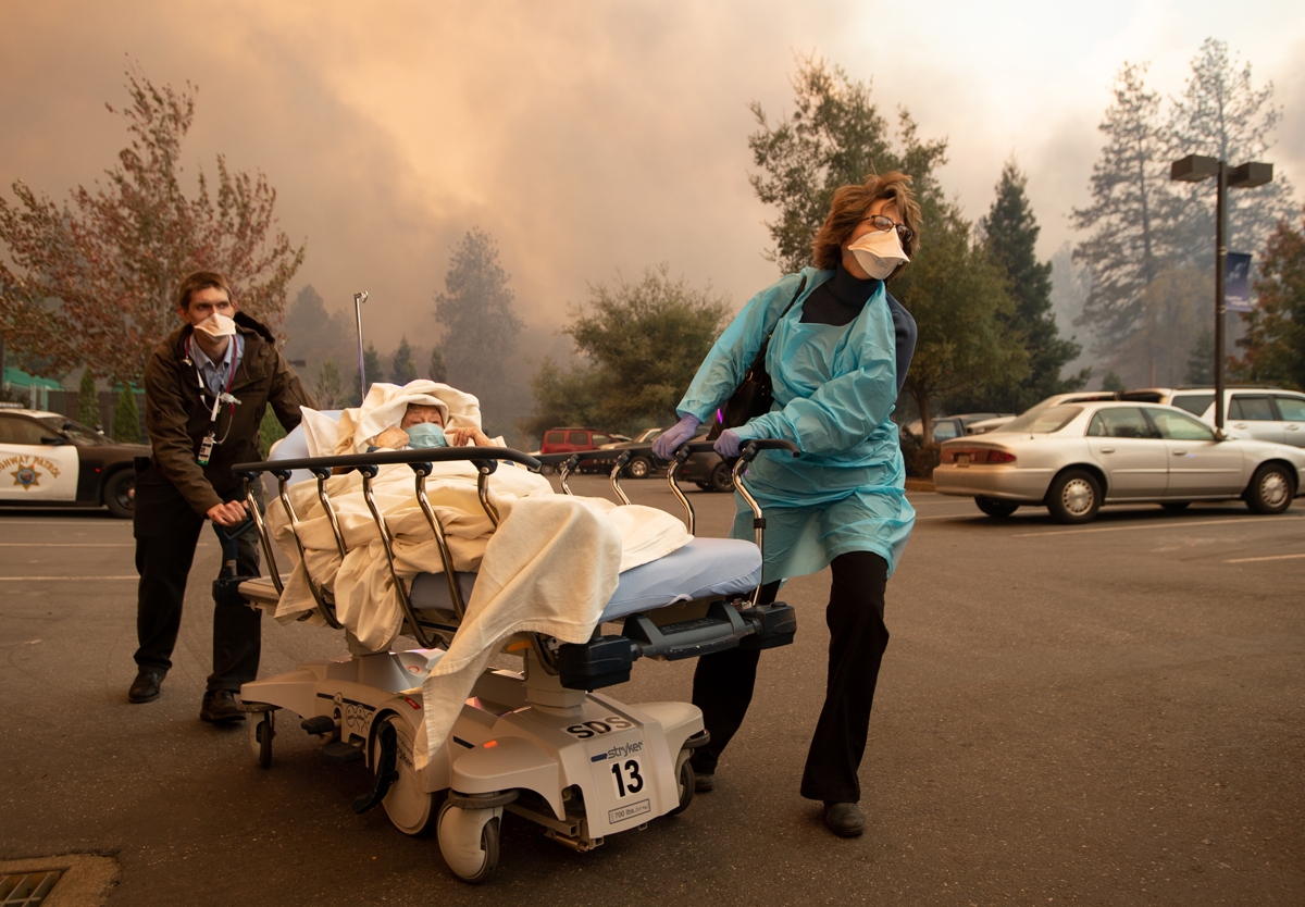 Patients are quickly evacuated from the Feather River Hospital as it burns down during the Camp fire in Paradise, California.
