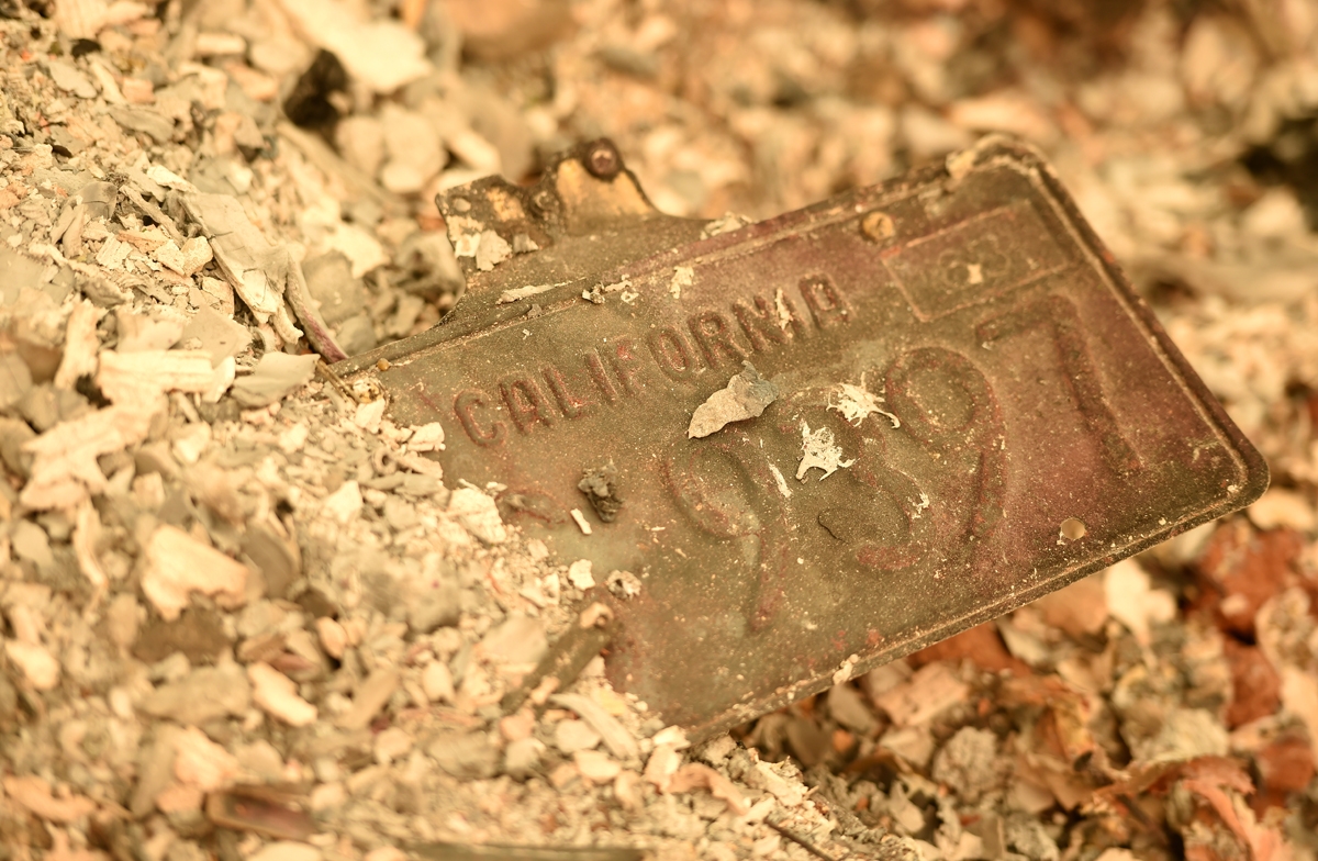 A California license plate is partially buried in a pile of ash at a burned residence after the Camp fire tore through the region in Paradise, California on November 12, 2018.