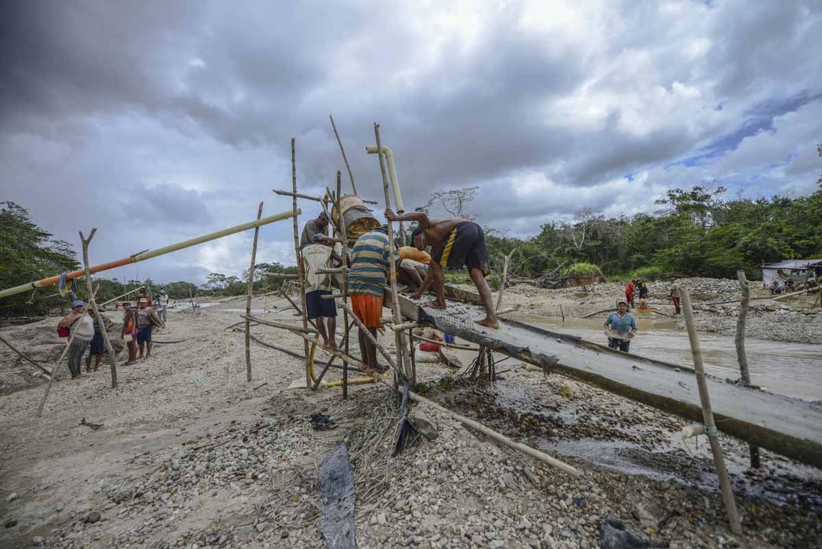 Men work on a sluice at a gold mine on the bank of a river in El Callao, Bolivar state, southeastern Venezuela on February 24, 2017. Although life in the mines of eastern Venezuela is hard and dangerous, tens of thousands from all over the country head fo