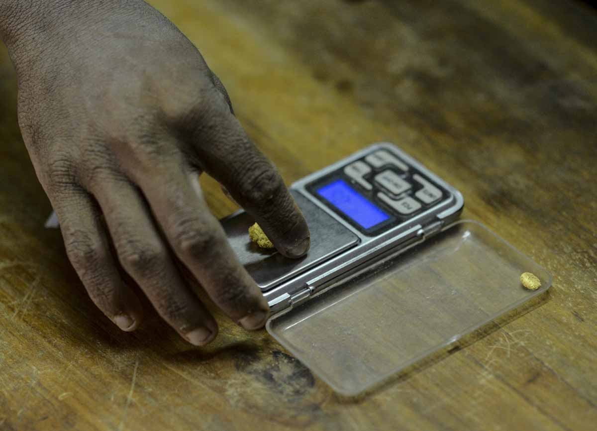 A man weighs a gold stone at a specialized store in El Callao, Bolivar state, southeastern Venezuela on February 25, 2017. Although life in the mines of eastern Venezuela is hard and dangerous, tens of thousands from all over the country head for the min