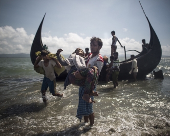 A Bangladeshi man helps Rohingya Muslim refugees to disembark from a boat on the Bangladeshi shoreline of the Naf river after crossing the border from Myanmar in Teknaf on September 30, 2017.