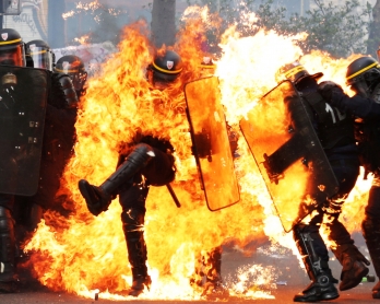 French CRS anti-riot police officers are engulfed in flames as they face protesters during a march for the annual May Day workers' rally in Paris on May 1, 2017. / AFP PHOTO / Zakaria ABDELKAFI