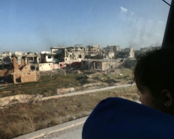 A convoy transporting Syrian civilians and rebel fighters drives past destroyed buildings in Arbin in Eastern Ghouta as they are evacuated from the opposition enclave to the village of Qalaat al-Madiq, some 45 kilometres northwest of the central city of H