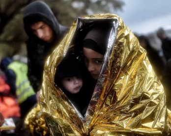 Niños cubiertos con una manta de emergencia tras llegar a la costa de Lesbos en octubre