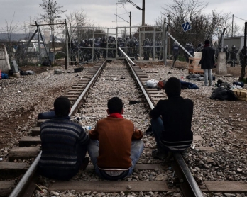 Los refugiados esperan sobre la vía del tren que conecta Grecia con Macedonia, delante de la frontera bloqueada por la policía macedonia el 29 de febrero de 2016