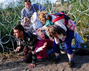 Una familia pasa por debajo de concertinas de seguridad en la frontera serbo-húngara, el 27 de agosto de 2015